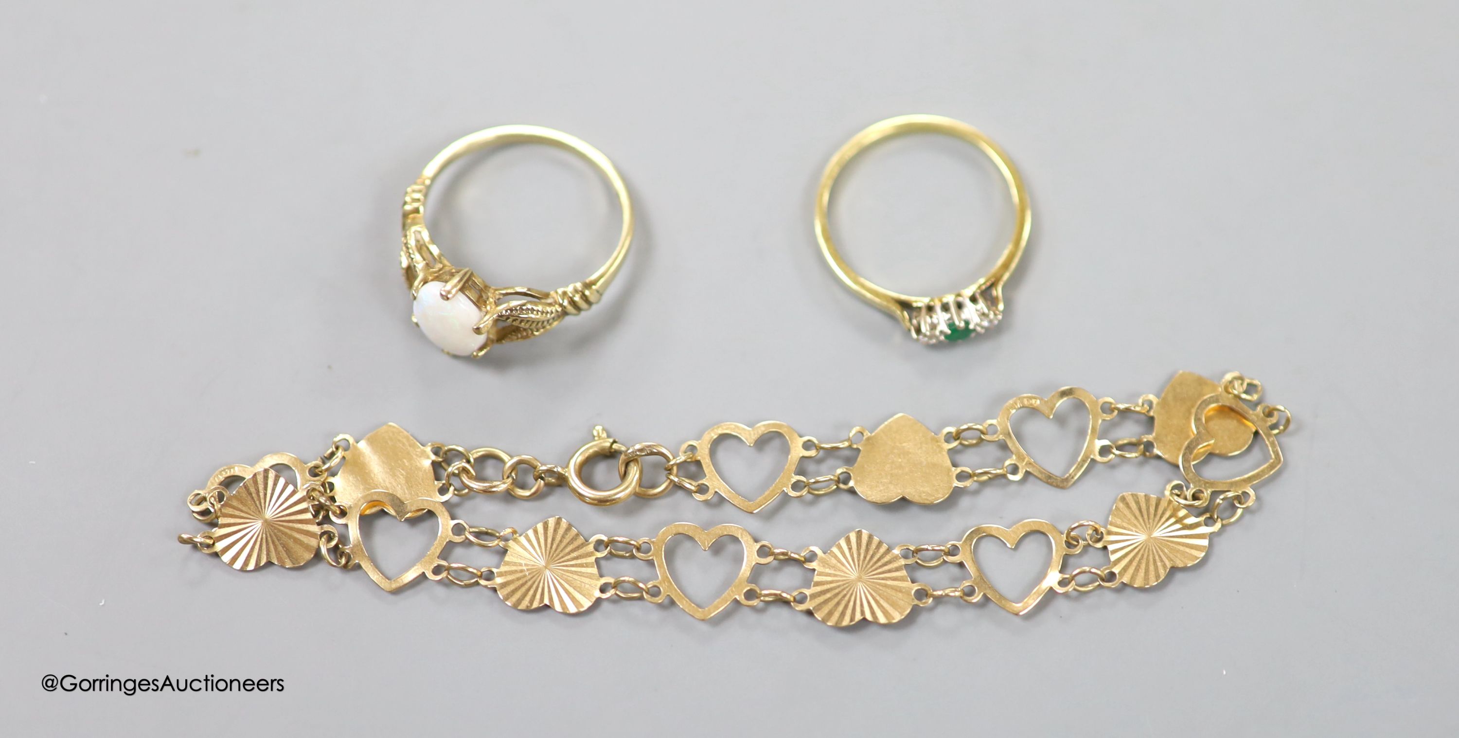 An 18ct gold, emerald and diamond three-stone ring, size M, gross 1.9 grams, a 9ct gold and opal ring and a 9ct gold 'heart' bracelet, gross 5.9 grams.